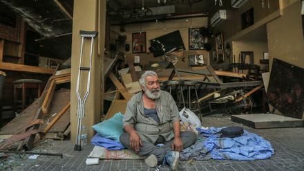 Auf der Straße. Ein Bewohner sitzt auf dem Boden vor einer zerstörten Bar.