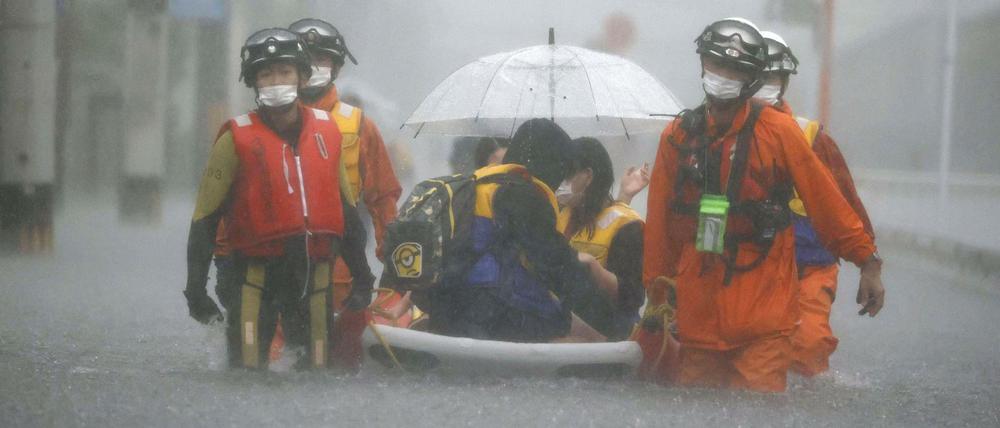Rettungskräfte ziehen in Kurume ein Boot durch die Straßen.