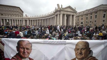 Pilger warten auf dem Petersplatz auf die Heiligsprechung von Johannes Paul II. (links) und Johannes XXIII.
