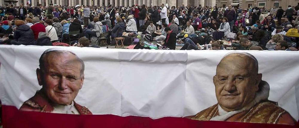 Pilger warten auf dem Petersplatz auf die Heiligsprechung von Johannes Paul II. (links) und Johannes XXIII.