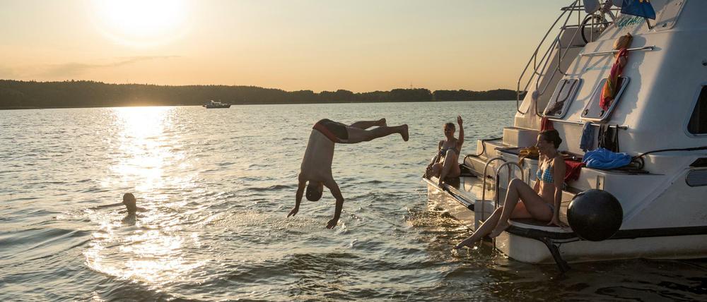 Menschen sonnen sich auf einem Boot und baden im Wasser.