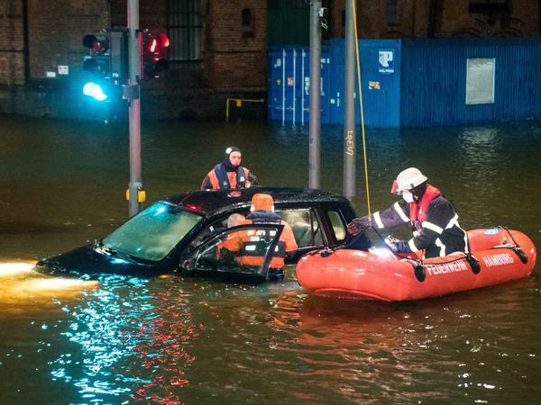 Feuerwehrleute retten in der Speicherstadt während einer Sturmflut beim Hochwasser der Elbe einen Mann aus seinem Auto.