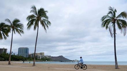 Ein Radfahrer fährt den leeren Waikiki Beach in Honolulu, Hawaii, entlang. 