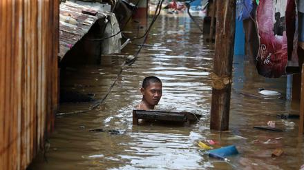 Monsunregen in Indonesien: Ein Mann schwimmt durch das Hochwasser einer überfluteten Straße in seiner Nachbarschaft.