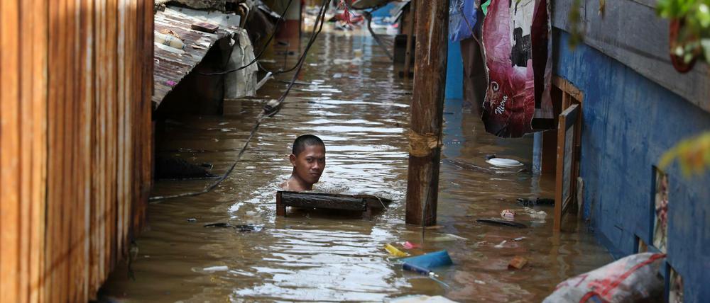 Monsunregen in Indonesien: Ein Mann schwimmt durch das Hochwasser einer überfluteten Straße in seiner Nachbarschaft.