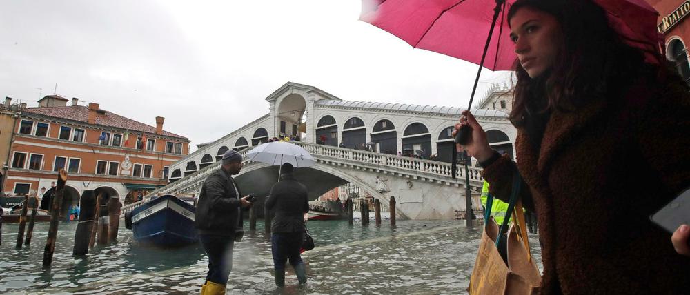 In Venedig gehen Passanten in der Nähe der Rialto-Brücke durch das Hochwasser.