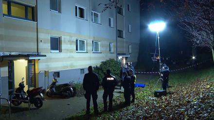 Polizisten stehen vor einem Wohnhaus. Ein Unbekannter hat in der Nacht eine Frauenleiche an der Straße eines Wohngebiets abgelegt.