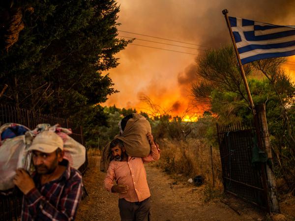 Menschen versuchen Teile ihrer Habe in Sicherheit zu bringen, während ein Waldbrand in einem Waldgebiet nördlich von Athen wütet. 
