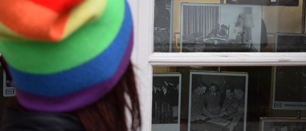 Ulrike Luther blickt durch ein Fenster am Haus der Wannsee-Konferenz auf ein Bild ihres Großvaters als NS-Beamter am Schreibtisch.