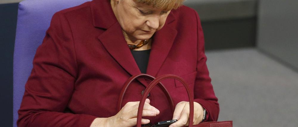 Bundeskanzlerin Angela Merkel schaut kurz mal auf ihr Handy.