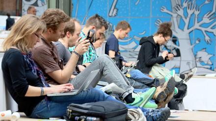 Besucher der Internetkonferenz Re:publica sitzen am 08.05.2013 in Berlin mit ihrem Laptop auf den Knien nebeneinander. 