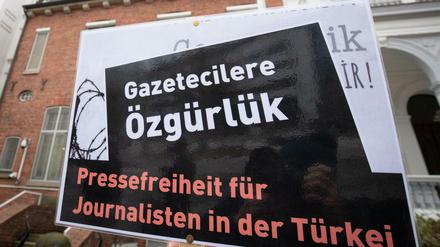  In Hamburg lebende Journalistinnen und Journalisten aus der Türkei stehen mit einem schwarzen Kranz vor dem Türkischen Konsulat. Die symbolische Aktion sollte ein Zeichen für Pressefreiheit und Solidarität mit inhaftierten Kollegen setzen. 