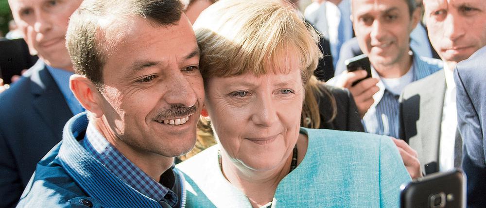 Bundeskanzlerin Angela Merkel (CDU) lässt sich am 10.09.2015 nach dem Besuch einer Erstaufnahmeeinrichtung für Asylbewerber der Arbeiterwohlfahrt (AWO) und der Außenstelle des Bundesamtes für Migration und Flüchtlinge in Berlin-Spandau für ein Selfie zusammen mit einem Flüchtling fotografieren. 