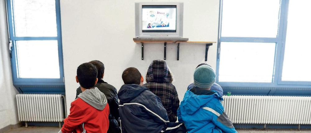 Kinder von Asylbewerbern sehen in der Landeserstaufnahmestelle in Baden-Württemberg fern.