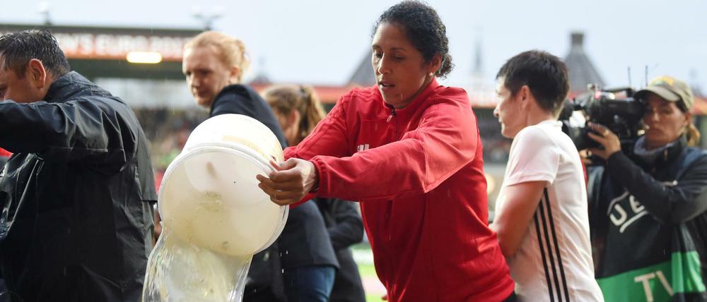 Deutschlands Trainerin Steffi Jones hilft nach Starkregen beim Entwässern des Spielfeldes für das EM-Viertelfinale. 