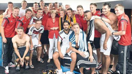 Gruppenbild mit Kanzlerin. Angela Merkel feiert mit der Jogi-Truppe den WM-Einstand. Foto: Guido Bergmann/AFP