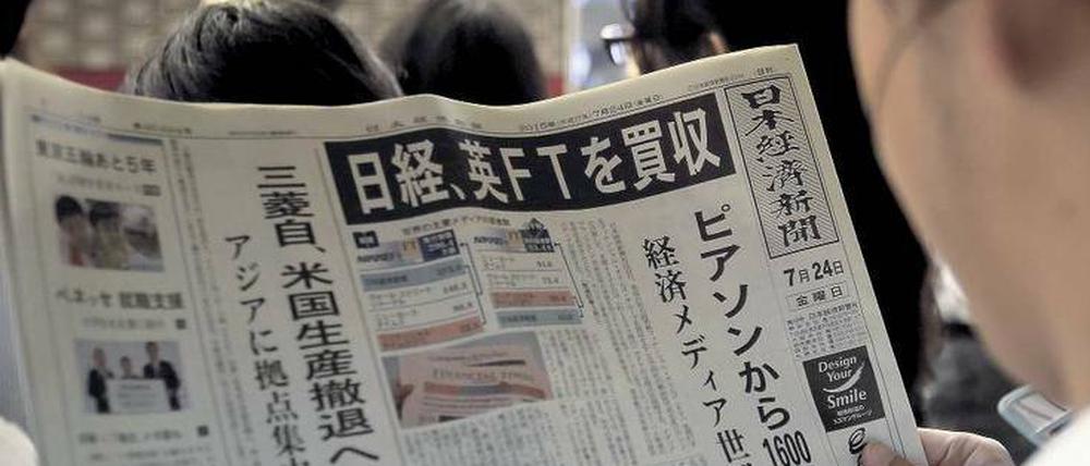 Aufregende Lektüre. Ein Mann in einem Tokioter Bahnhof liest in der „Nikkei“-Ausgabe vom 24. Juli den Aufmacher über den Kauf der britischen „Financial Times“. 