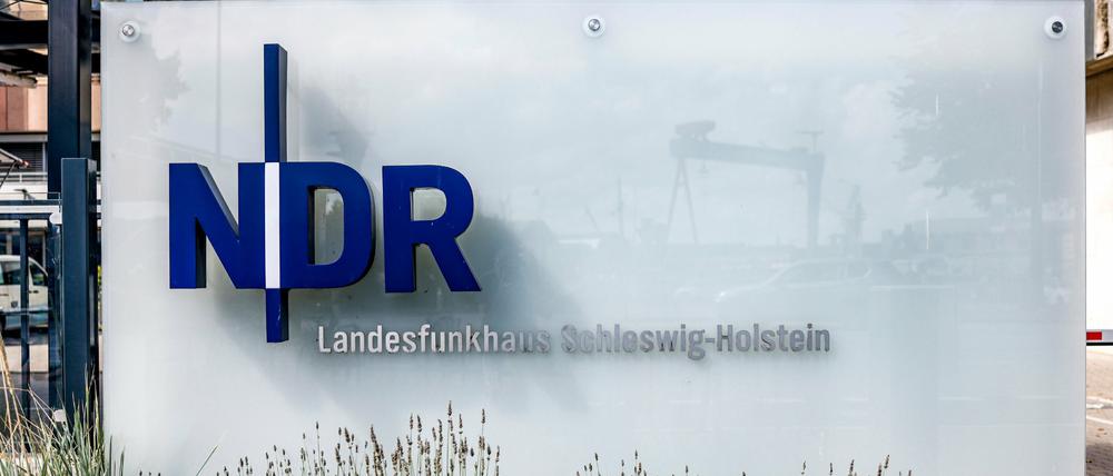 Das NDR-Logo ist an der Einfahrt zum Landesfunkhaus Schleswig-Holstein auf einer Glasplatte angebracht. 