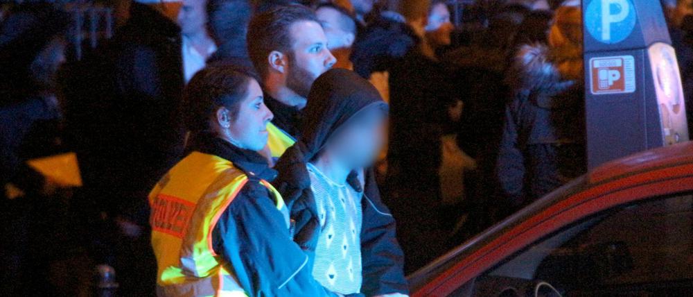 Ein Mann wird am 01.01.2016 in Köln am Hauptbahnhof von Polizeibeamten abgeführt. Welcher Nationalität?