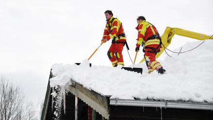 Feuerwehrleute räumen in Inzell den Schnee vom Dach eines Hauses. Neuer Schnee ist bereits im Anmarsch.