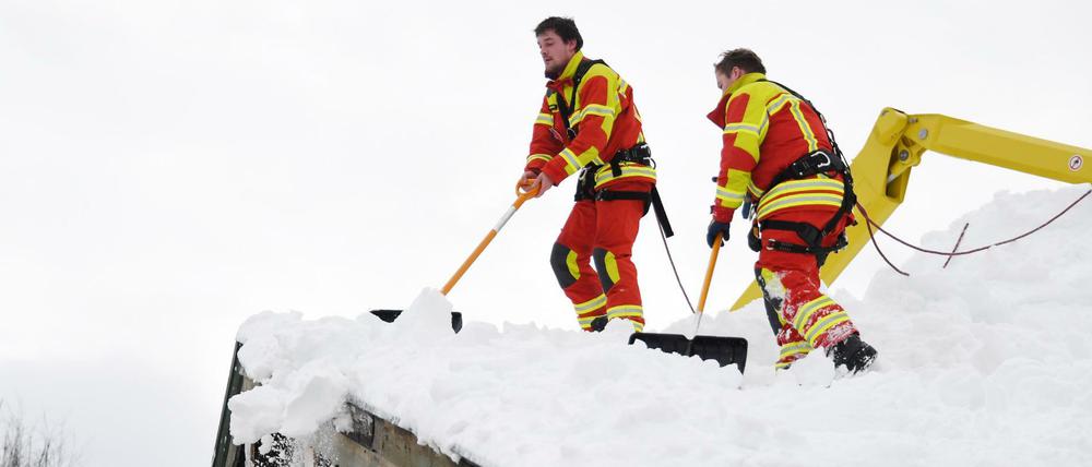 Feuerwehrleute räumen in Inzell den Schnee vom Dach eines Hauses. Neuer Schnee ist bereits im Anmarsch.