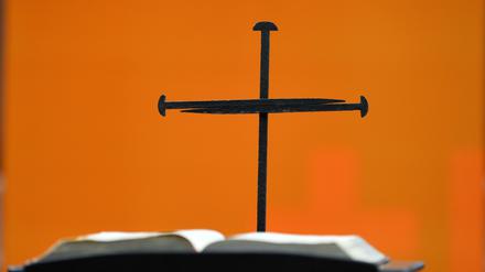 Ein Nagelkreuz steht hinter einer Bibel.