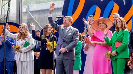 König Willem-Alexander steht mit seiner Ehefrau Maxima und den gemeinsamen Töchtern auf der Bühne und winkt.