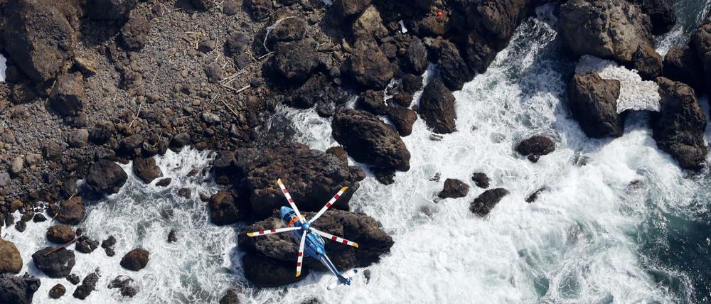 Ein Helikopter sucht die Küste der japanischen Halbinsel Shiretoko nach Vermissten ab.
