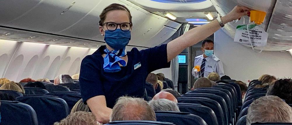 Neue Normalität beim ersten Flug nach Mallorca: Flugbegleiterin und Reisende mit Maske. 