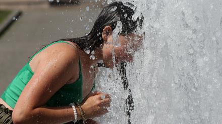 Eine junge Frau kühlt sich Anfang August in einem Citybrunnen in Berlin ab.
