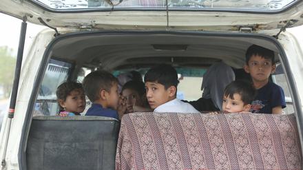 Binnenvertriebene Kinder, die in ihre Heimatprovinzen in Afghanistan zurückgeschickt werden sollen, sitzen in einem Auto. 