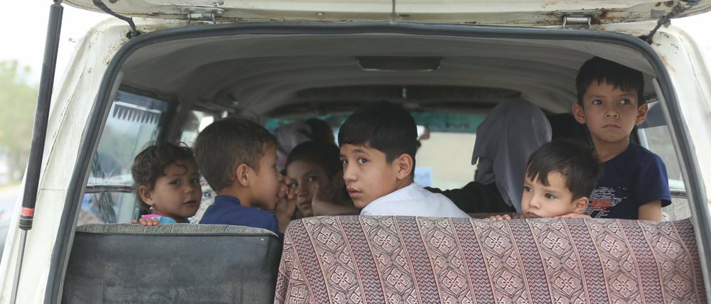 Binnenvertriebene Kinder, die in ihre Heimatprovinzen in Afghanistan zurückgeschickt werden sollen, sitzen in einem Auto. 