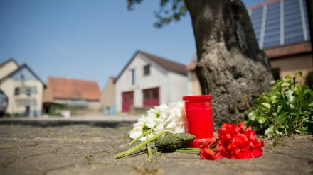 Blumen und eine Kerze liegen am Samstag in Leutershausen an einem Tatort, an dem am Vortag eine Frau erschossen wurde.