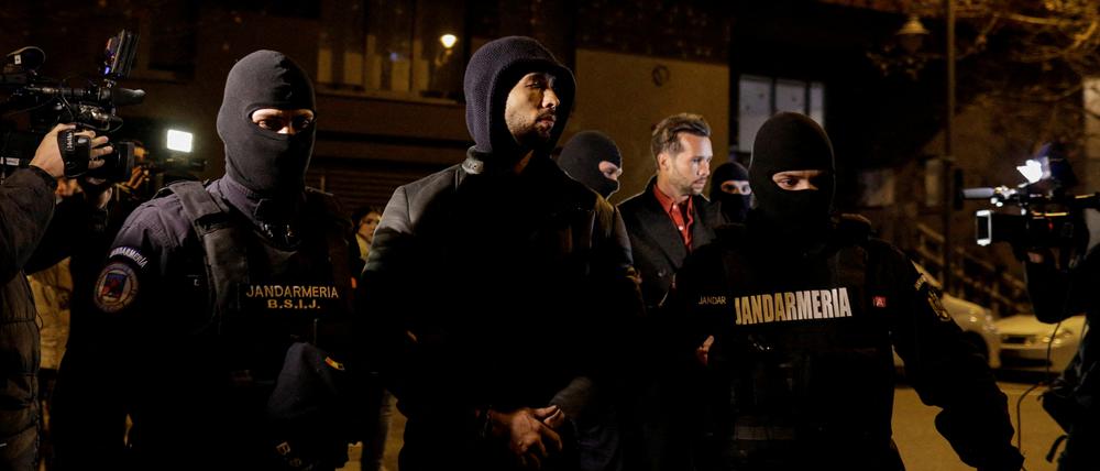 Andrew Tate und Tristan Tate werden von Polizeibeamten vor dem Sitz der Direktion für die Untersuchung von organisierter Kriminalität und Terrorismus in Bukarest (DIICOT) eskortiert.