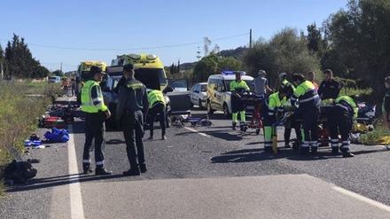Rettungskräfte und Polizisten stehen am Unfallort, an dem ein Auto in eine Gruppe von 15 Radfahrern aus Deutschland gefahren ist. 