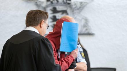 Der Angeklagte wird von einem Justizbeamten in einen Gerichtssaal des Landgerichts Stuttgart geführt.