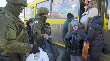 Soldaten beobachten, wie Evakuierte aus der ukrainischen Region Charkiw an der russischen Grenze aus einem Bus aussteigen (Archivbild).