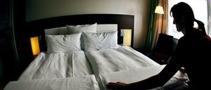 Ein Zimmermädchen macht in einem Hotel ein Bett. 