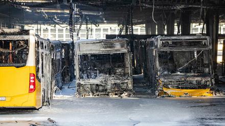 Ausgebrannte Busse stehen nach den Löscharbeiten in einem Depot für Busse im Löschschaum. 