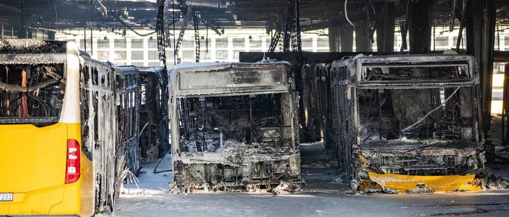 Ausgebrannte Busse stehen nach den Löscharbeiten in einem Depot für Busse im Löschschaum. 