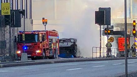 Einsatzkräfte der Feuerwehr stehen nach der Explosion eines Busses im Stadtzentrum von Stockholm. 