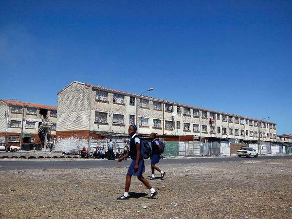 Vier Millionen Menschen leben in den armen Vorstädten Kaptstadts, den sogenannten Cape Flats. Hier laufen zwei Schulmädchen im Bezirk Hanover Park an den heruntergekommenen Wohnsiedlungen vorbei. 