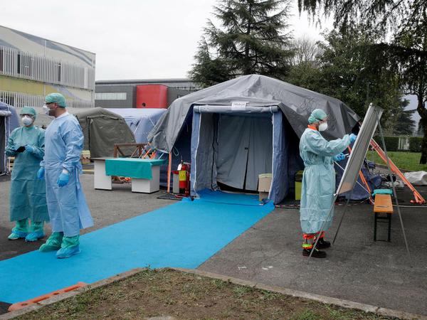 Sanitäter arbeiten in Brescia vor Notfallzelten, die in der Nähe eines Krankenhauses errichtet wurden. 