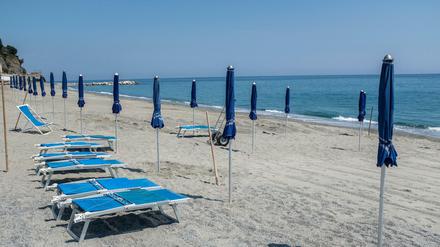 Strandliegen und Sonnenschirme stehen in Ligurien am Strand von Ligurien. 