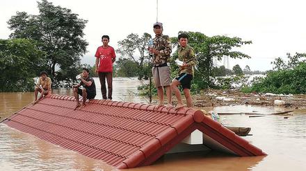 Laos, Attapeu: Dorfbewohner haben sich vor den Wassermassen auf die Dächer eines Hauses gerettet.