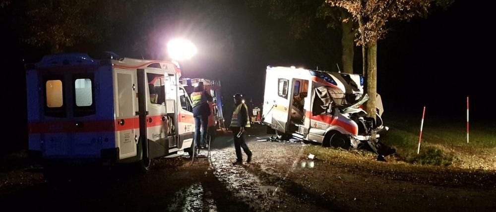 Rettungskräfte stehen am Donnerstag an einer Unfallstelle bei Langen (Niedersachsen), an der ein Rettungswagen gegen einen Straßenbaum geprallt ist.