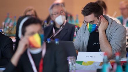 Eine Teilnehmerin und ein Teilnehmer mit Regenbogen-Maske bei der Dritten Synodalversammlung der deutschen Katholiken