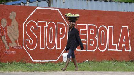 Eine Frau in Sierra Leone geht an einer Wand mit der Aufschrift "Stop Ebola" vorbei. In dem westafrikanischen Land wurde eine erneute Ausgangssperre angekündigt. 