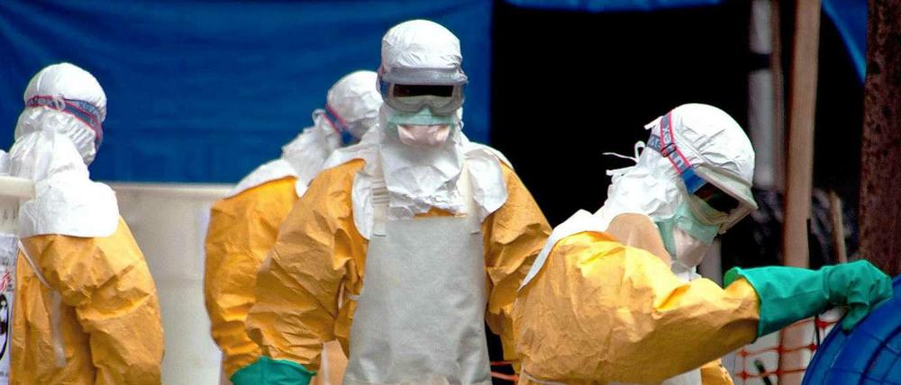 Mitarbeiter in Schutzanzügen reinigen den Patientenbereich in einem Ebola-Behandlungszentrum.