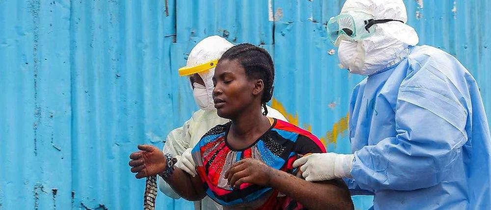 Eine an Ebola erkrankte Frau in Liberia wird von Klinikmitarbeitern in Monrovia betreut.
